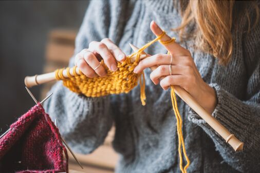 Frau strickt, Fokus auf Händen und Stricknadeln